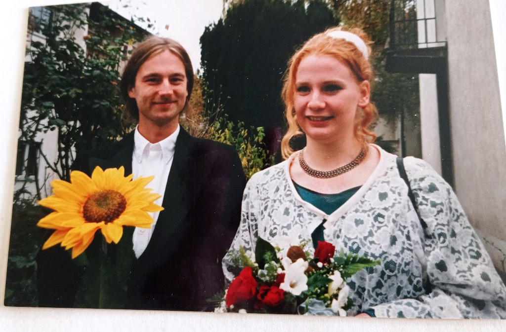 Hochzeitspaar. Frau mit rot-weißen Blumenstrauß, Mann mit großer Sonnenblume