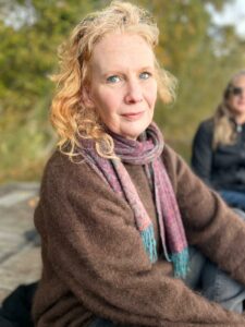 Frau draußen sitzend, in Kamera blickend